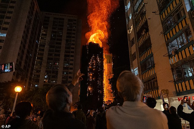People look at flames engulfing a building after a fire broke out at Wang Fuk Court, a residential estate in the Tai Po district of Hong Kong's New Territories, Wednesday, November 26, 2025