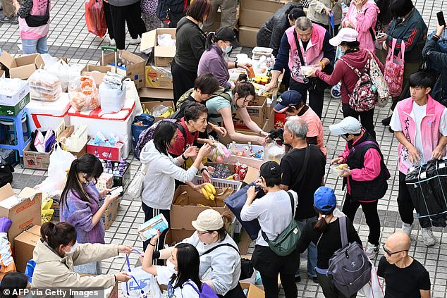 Volunteers give out food and drinks after a major fire swept through several apartment blocks at the Wang Fuk Court residential estate in Hong Kong's Tai Po district on November 27, 2025