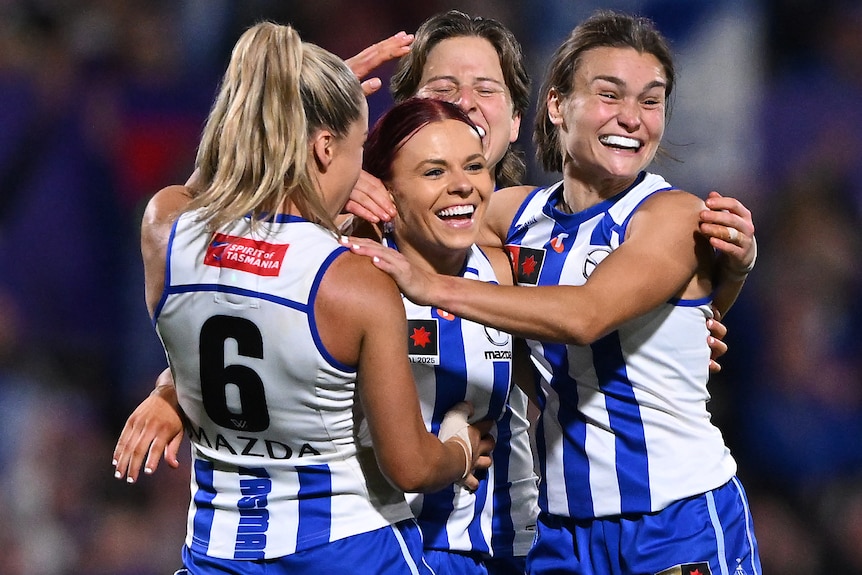 Four Kangaroos AFLW players celebrate a goal in the grand final.