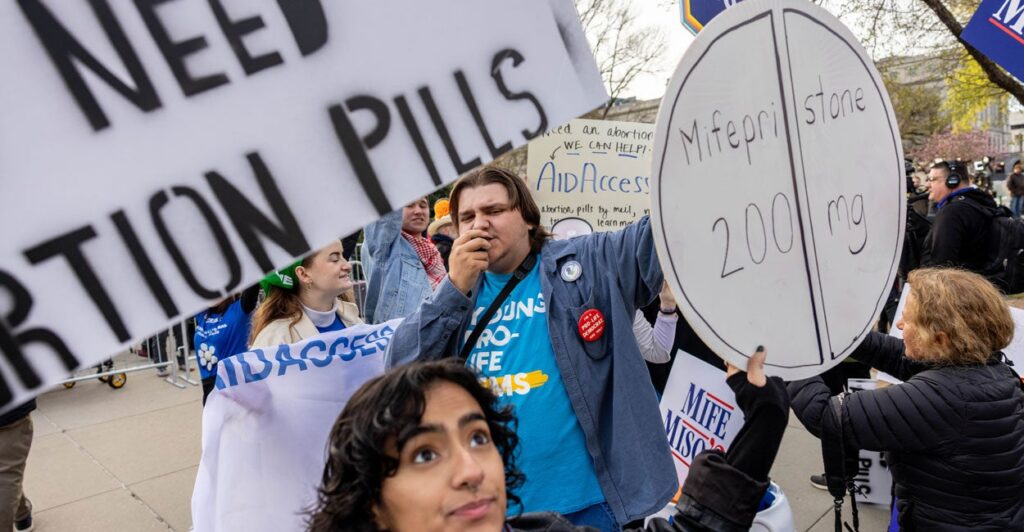Demonstrators hold up signs outside U.S. Supreme Court, including one that says Mifepristone 200mg.