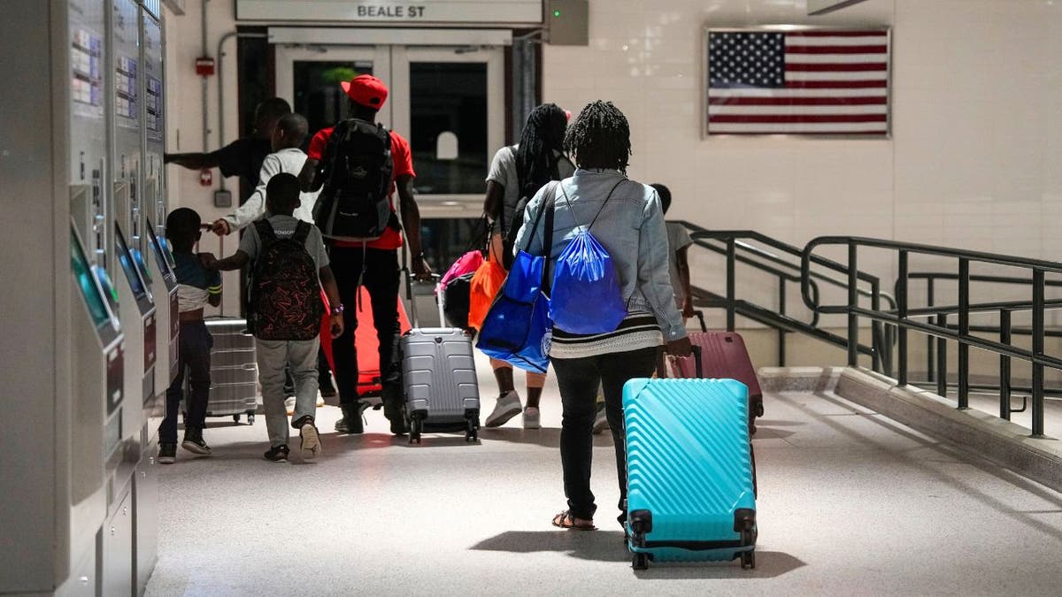 Haitian migrant families with luggage walking through a Massachusetts T station.