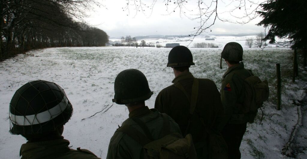 Black-and-white photo of U.S. soldiers overlooking site of Battle of the Bulge.
