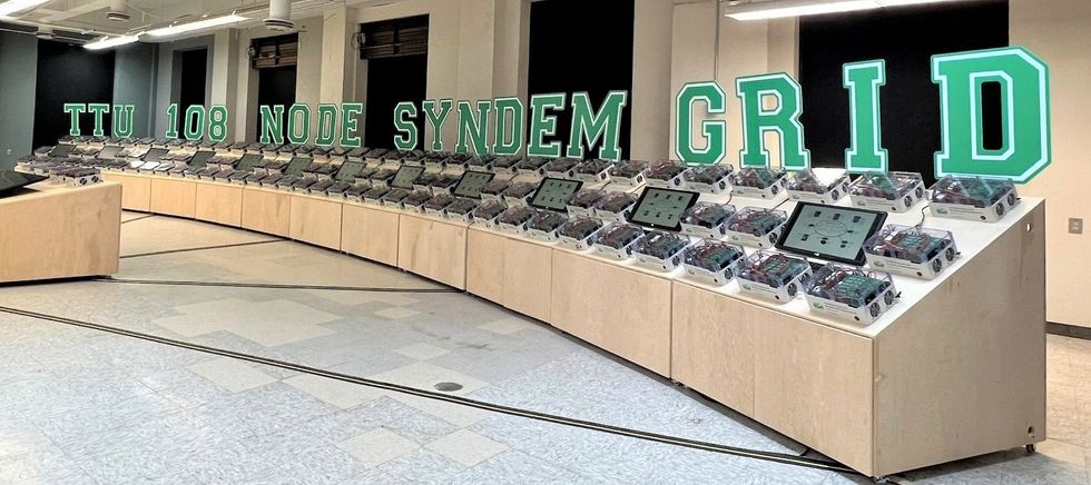 An array of touch screens and Syndem converters in a control room.