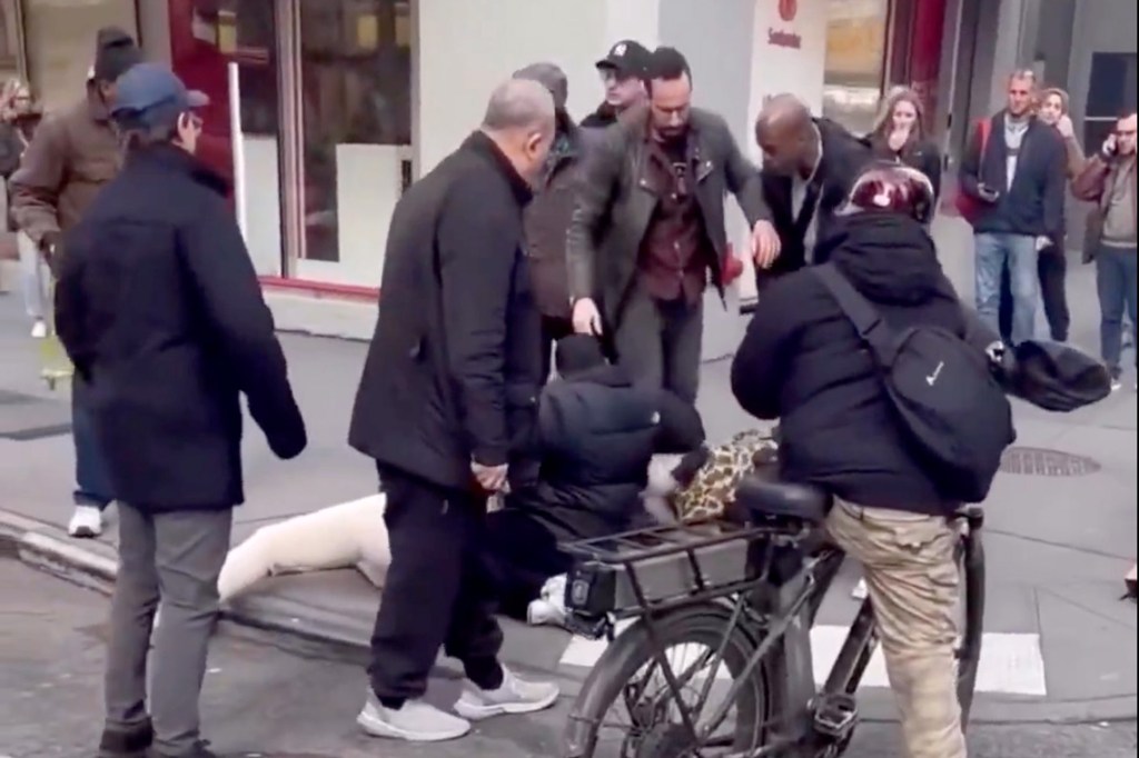 Several people intervening during a dog attack on a child on a city street.