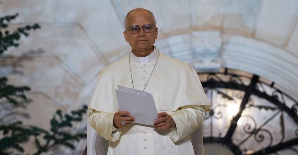Pope Leo XIV stands, holding a white folder.