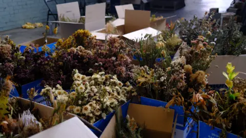 BBC/Katy Watson Cardboard boxes full of flower bouquets in a warehouse waiting to be sorted