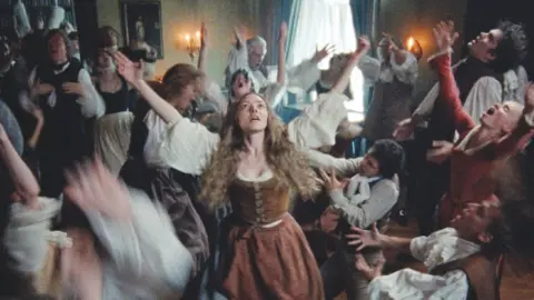 Searchlight Amanda Seyfried with her hands in the air, surrounded by people dancing and singing