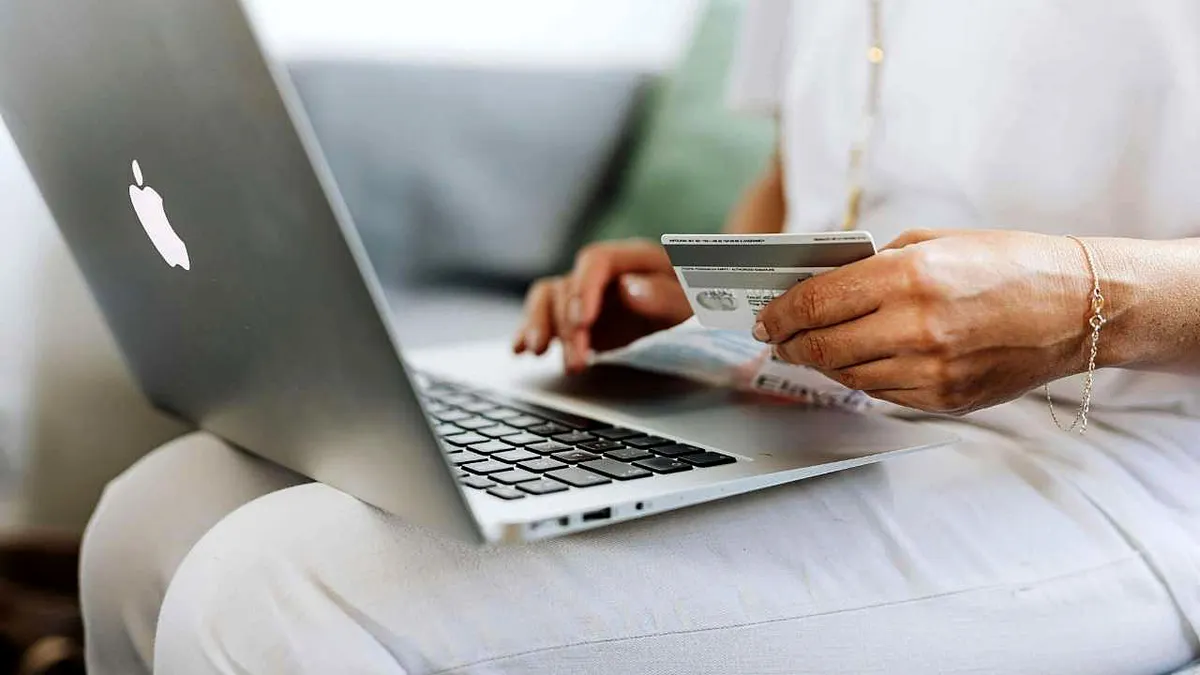 A woman holds a credit card as she types on her laptop.