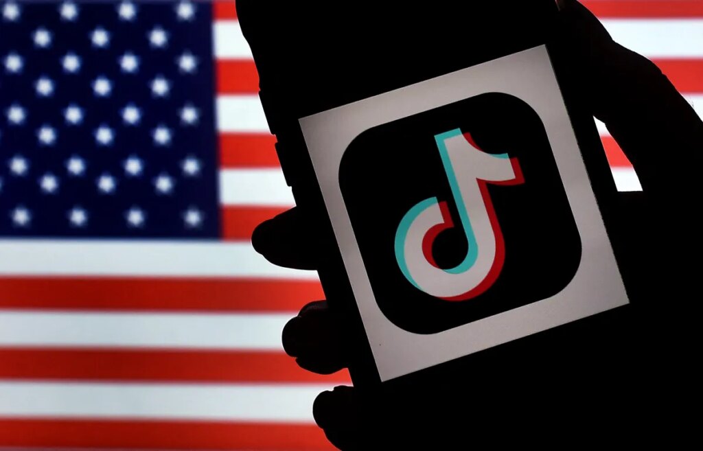 In this photo illustration, the social media application logo, TikTok is displayed on the screen of an iPhone on an American flag background on August 3, 2020 in Arlington, Virginia. - The US Senate voted on August 6, 2020, to bar TikTok from being downloaded onto US government employees