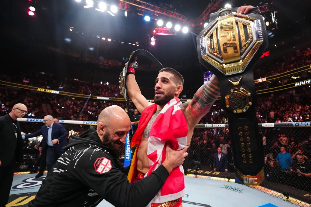 UFC fighter holding championship belt.