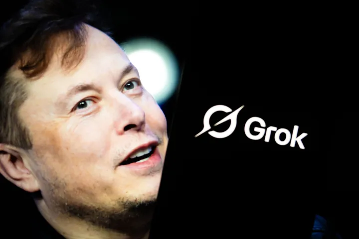 xAI's 'Grok' logo is seen displayed on a mobile phone screen in front of a picture of Elon Musk in a photo illustration. (Photo by Didem Mente/Anadolu via Getty Images)