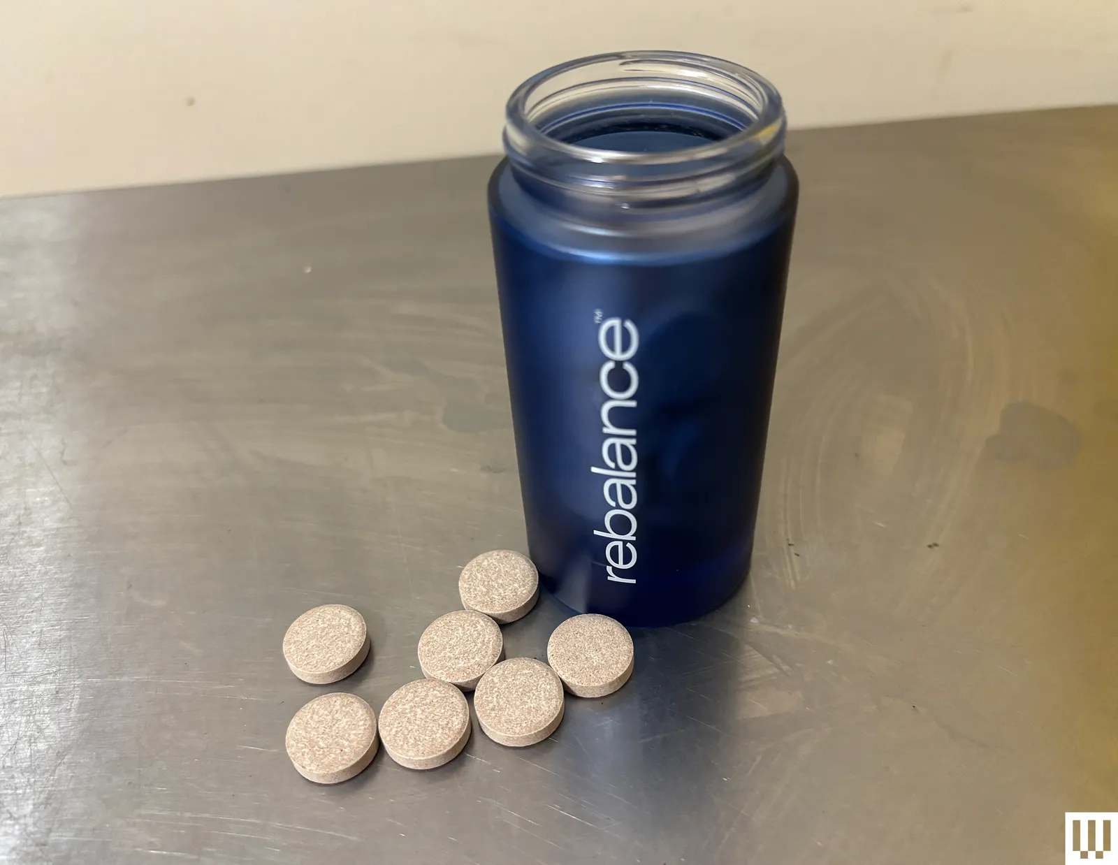 Jar with blue labeling beside circular tablets on the counter