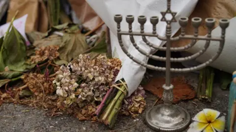 Reuters A menorah pictured alongside a wilting bunch of flowers at the Bondi memorial