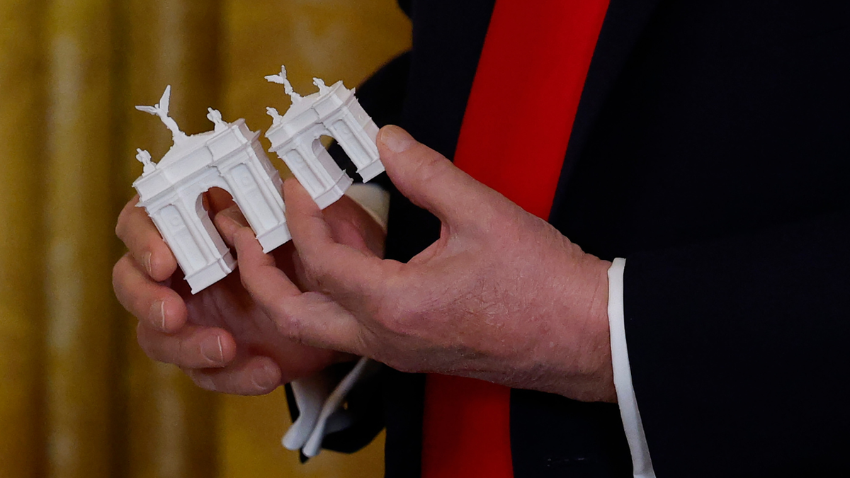 President Donald Trump holds models of a new arch during a fundraising dinner